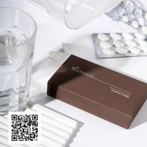 Essens Vitamin D Elite tablets on a desk next to a glass of water